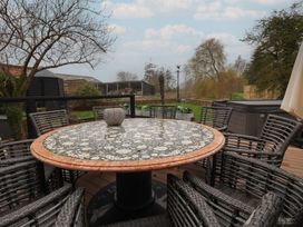 An outdoor dining area with a round table and chairs at Mill Race Cottage in Driffield