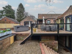 An outdoor seating area with a hot tub and dining set at Mill Race Cottage in Driffield