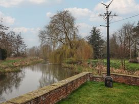 A river with a brick wall and weather vane at Mill Race Cottage in Driffield