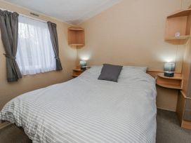 A bedroom with a bed and shelves at Ger Y Mor in New Quay