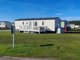A static caravan with a deck and parking sign at 18 Fallows Fall in Leven