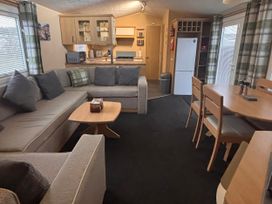 A living room with a sofa and dining area at 18 Fallows Fall in Leven