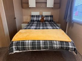 A bed with a plaid blanket and a toy bear at 18 Fallows Fall in Leven