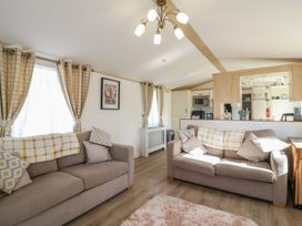 A living room with sofas and kitchen counter at 2 bed Caravan Stowmarket