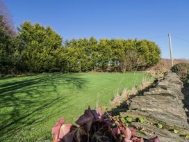 A garden with a stone wall and greenery at Linden Lea in Grange-Over-Sands