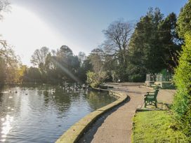 A park with a path beside a pond and a bench at Linden Lea Grange-Over-Sands