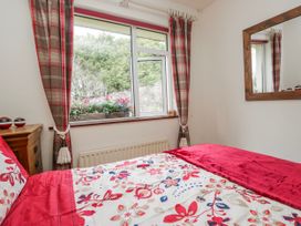 A bedroom with a red bedspread and a window at Linden Lea Field Broughton near Cartmel