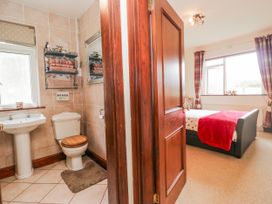 A bathroom with a sink and toilet adjacent to a bedroom with a bed at Linden Lea Field Broughton near Cartmel
