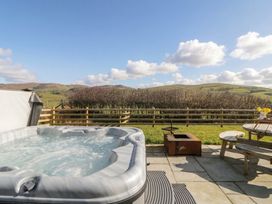 An outdoor area with a hot tub and a wooden table at Daverneithon 4 near Llandrindod Wells