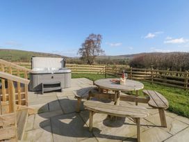 An outdoor area with a hot tub and a wooden table at Daverneithon 4 near Llandrindod Wells