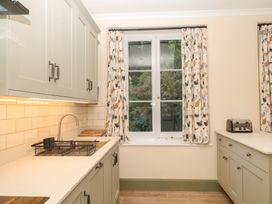 A kitchen with cabinets and a window at Lukesland Wing in Ivybridge