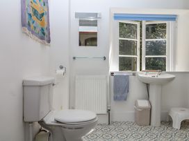 A bathroom with a toilet, sink, and window at Lukesland Wing in Ivybridge
