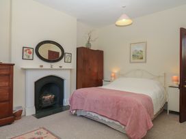 A bedroom with a bed, wardrobe, and fireplace at Lukesland Wing in Ivybridge
