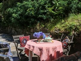 An outdoor seating area with a table, chairs, and flowers at Lukesland Wing in Ivybridge