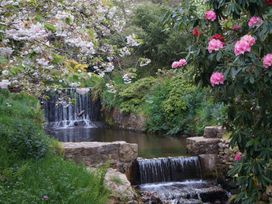 A garden with a waterfall and flowering trees at Lukesland Wing near Ivybridge