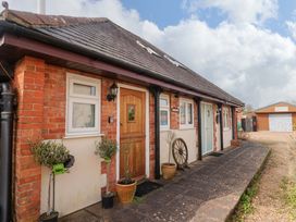 A front view of a brick house with plants and a paved pathway at The Coach House in Dorchester