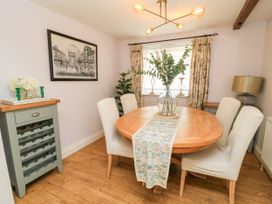 A dining room with a round table and chairs at The Coach House Near Charminster