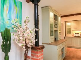A kitchen with a plant, cabinet, and art at The Coach House Near Charminster