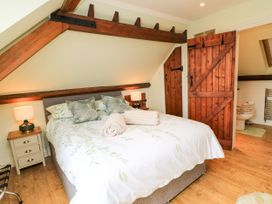A bedroom with a bed and wooden features at The Coach House Near Charminster