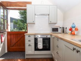 A kitchen with a window, oven, microwave and kettle at The Cottage in Sampford Courtenay