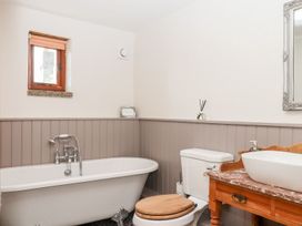 A bathroom with a bathtub, toilet, and sink at The Cottage in Sampford Courtenay