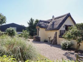 A house with a thatched roof and a garden at The Cottage in Sampford Courtenay