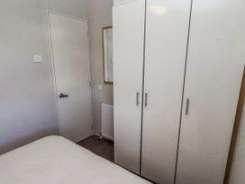 A bedroom with a bed and wardrobe at 75 Morpeth Mews in Wooler