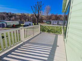 A deck view overlooking caravans and trees at 75 Morpeth Mews in Wooler
