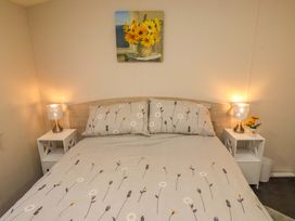 A bedroom with a bed and nightstands at Gardeners Lodge