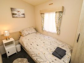 A bedroom with a bed and bedside table at Gardeners Lodge 