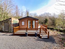 A cabin with a deck by a pond at Gardeners Lodge