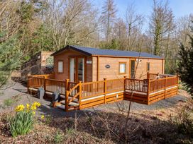 A lodge with decking and steps surrounded by trees at Gardeners Lodge