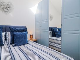 A bedroom with a bed, pillows, nightstand, and wardrobe at Le Petit Glen in Uplyme