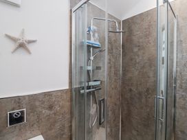 A shower with glass doors and a starfish on the wall at Le Petit Glen in Uplyme