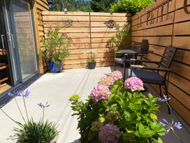 An outdoor seating area with potted plants and a wooden fence at Le Petit Glen in Uplyme