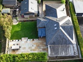 An outdoor view of a garden with patio furniture and sheds at Le Petit Glen in Uplyme