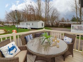 An outdoor seating area with a table and chairs at Hedgerow Lodge in Grange-Over-Sands