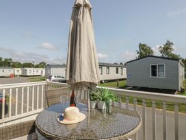 An outdoor seating area with a table and umbrella at Hedgerow Lodge Haven Lakeside near Grange-Over-Sands