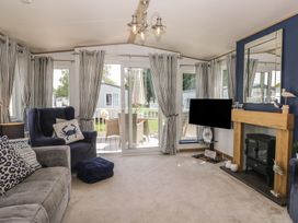 A living room with a sofa and TV at Hedgerow Lodge in Haven Lakeside near Grange-Over-Sands