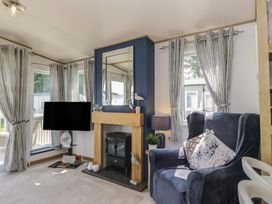 A living room with a fireplace and television at Hedgerow Lodge near Haven Lakeside Grange-Over-Sands