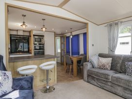A living room with a sofa and dining area at Hedgerow Lodge in Haven Lakeside near Grange-Over-Sands