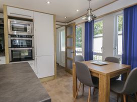 A kitchen with appliances and dining area at Hedgerow Lodge near Haven Lakeside Grange-Over-Sands