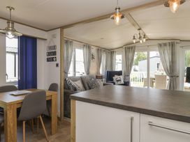 A living room with a sofa, table, and windows at Hedgerow Lodge Haven Lakeside near Grange-Over-Sands