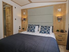 A bedroom with a bed and bedside tables at Hedgerow Lodge Haven Lakeside near Grange-Over-Sands