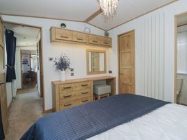 A bedroom with a dresser and mirror at Hedgerow Lodge Haven Lakeside near Grange-Over-Sands