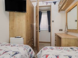 A bedroom with a wardrobe and television at Hedgerow Lodge near Haven Lakeside Grange-Over-Sands