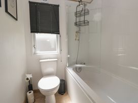 A bathroom with a toilet and a bathtub with a shower at Hedgerow Lodge near Haven Lakeside