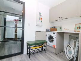 A laundry room with a washing machine and a bench at Trwyn Cam Brynrefail near Llanberis