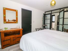 A bedroom with a bed, storage cabinet, and mirror at Trwyn Cam in Brynrefail near Llanberis