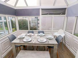 A dining area with a table and chairs in a conservatory at The Wool Pack in Tenby